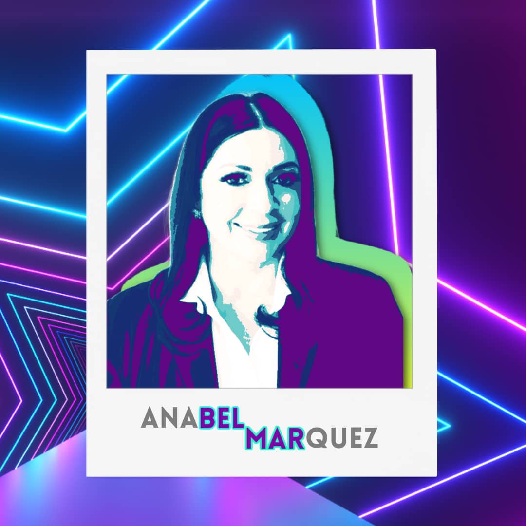 black and white image of anabel marquez smiling at the camera, she has dark flowy hair, large earings, and has her makeup done.
